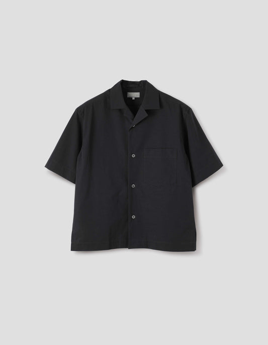 Black short-sleeved shirt with revere collar, mother of pearl buttons, chest patch pocket and side split hem. Front flat lay view. 