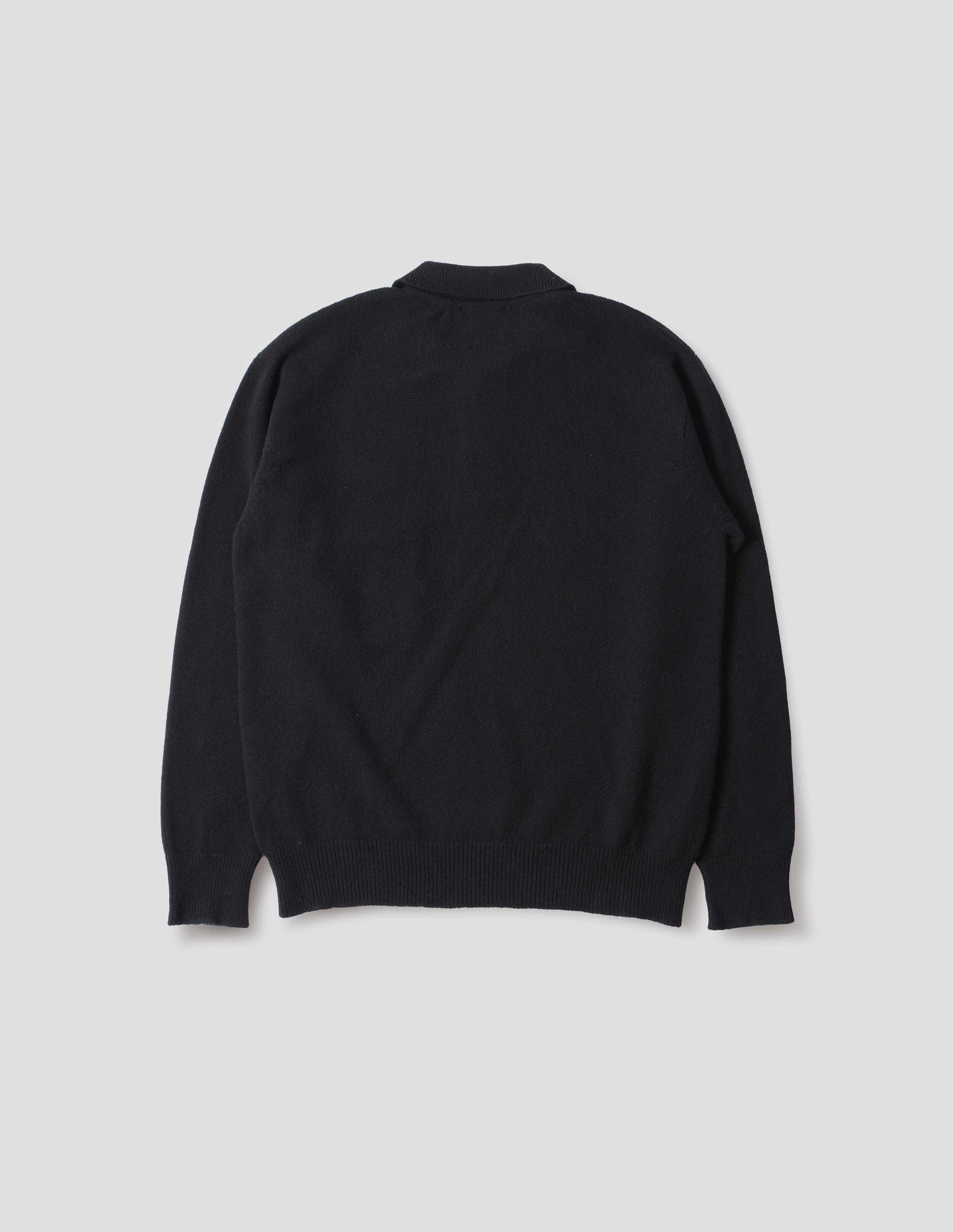 Black merino cashmere polo shirt with dropped sleeve and rib collar, cuffs and hem. Back flat lay view.