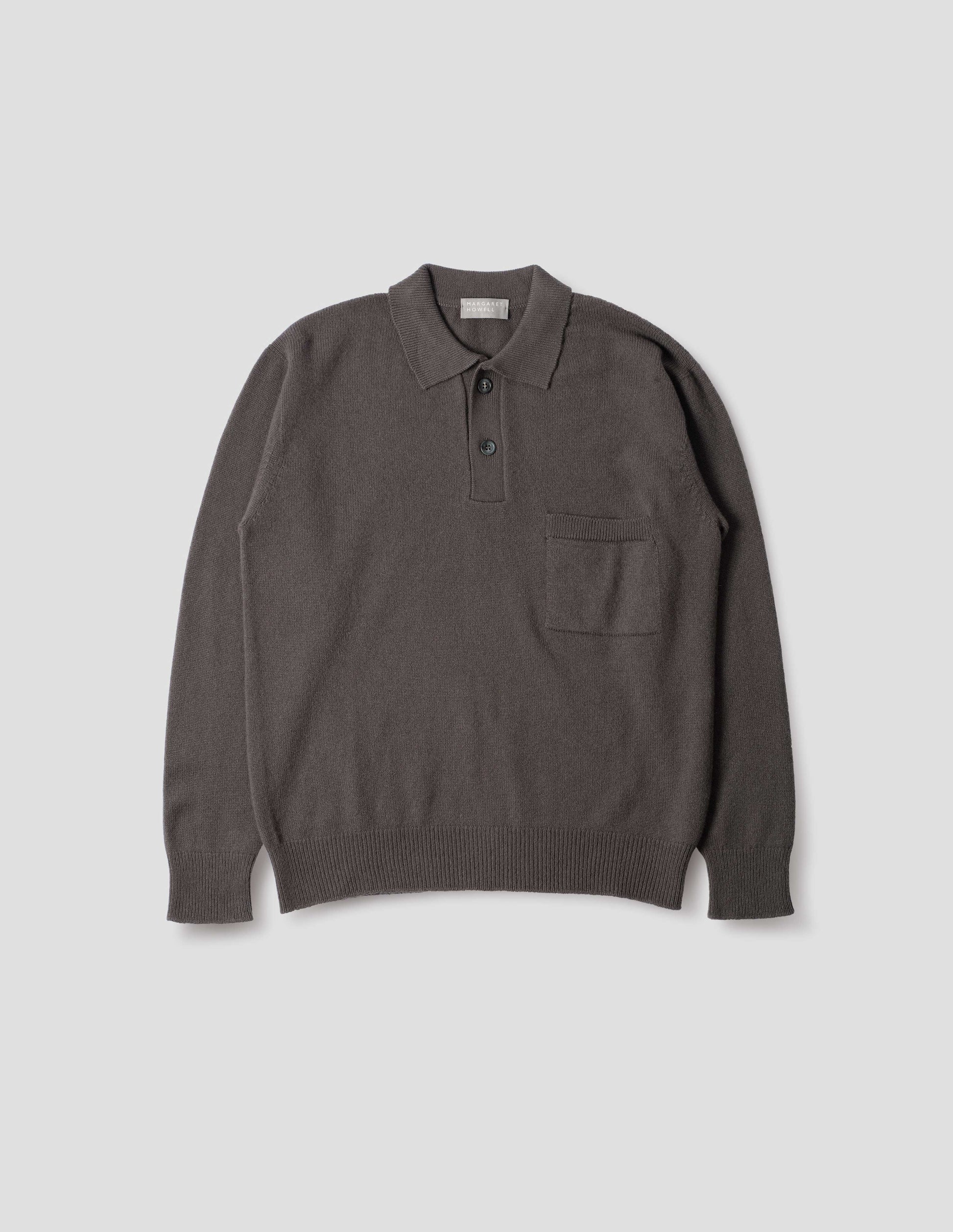 Dark grey merino cashmere polo shirt with dropped sleeve, integral chest pocket, horn button closure and rib collar, cuffs and hem. Front flat lay view.