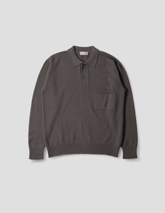 Dark grey merino cashmere polo shirt with dropped sleeve, integral chest pocket, horn button closure and rib collar, cuffs and hem. Front flat lay view.