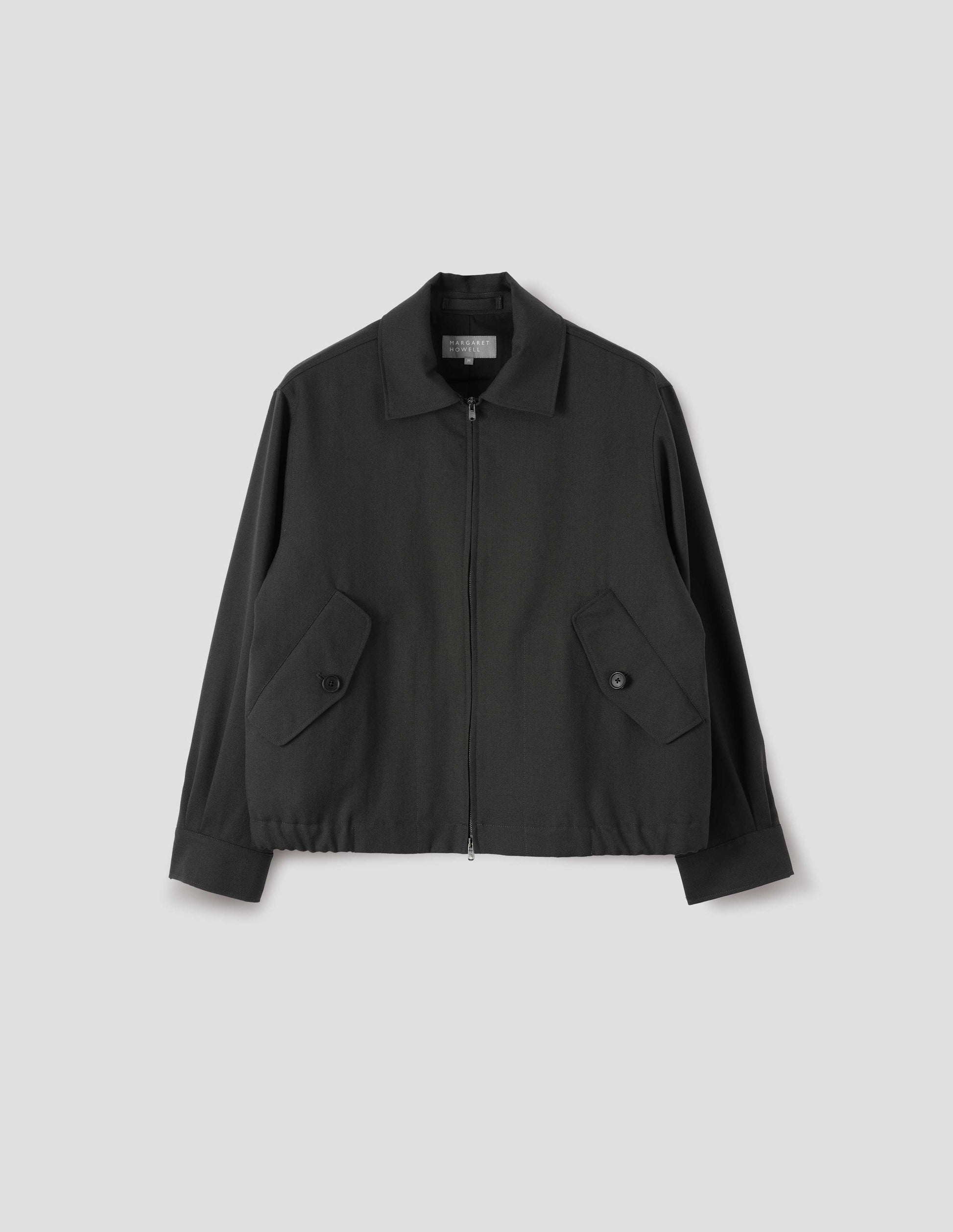 Dark grey wool jacket with two way zip fastening, elasticated waistband, tab shirt cuffs and button flap pockets. Front flat lay view.