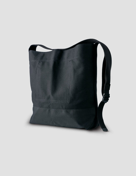 Black heavy cotton canvas shoulder tote bag with adjustable contrast nylon shoulder strap. Back side angle flat lay.