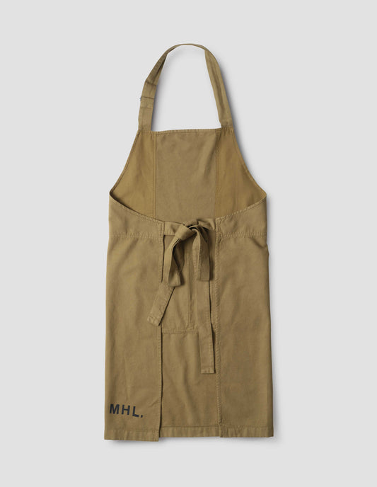 Beige heavy cotton canvas apron with adjustable overhead strap, tie back straps and black MHL. stamped logo on right hand side. Back flat lay view.