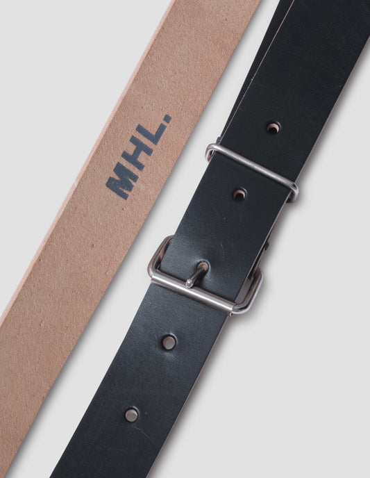 Black leather belt with simple silver roller buckle and metal keeper and raw leather edge and colour contrast inside. MHL. logo stamped on centre of inside. Close up detail flat lay.