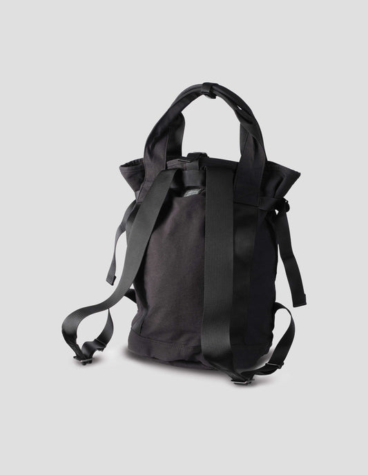 Black backpack with contrast webbing on handles and shoulder straps, side strap adjustors. Back flat lay view.