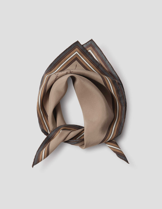 Beige folded and tied silk neck scarf with white, brown and grey contrast borders, hand rolled edges and Margaret Howell logo. Close up flat lay view.