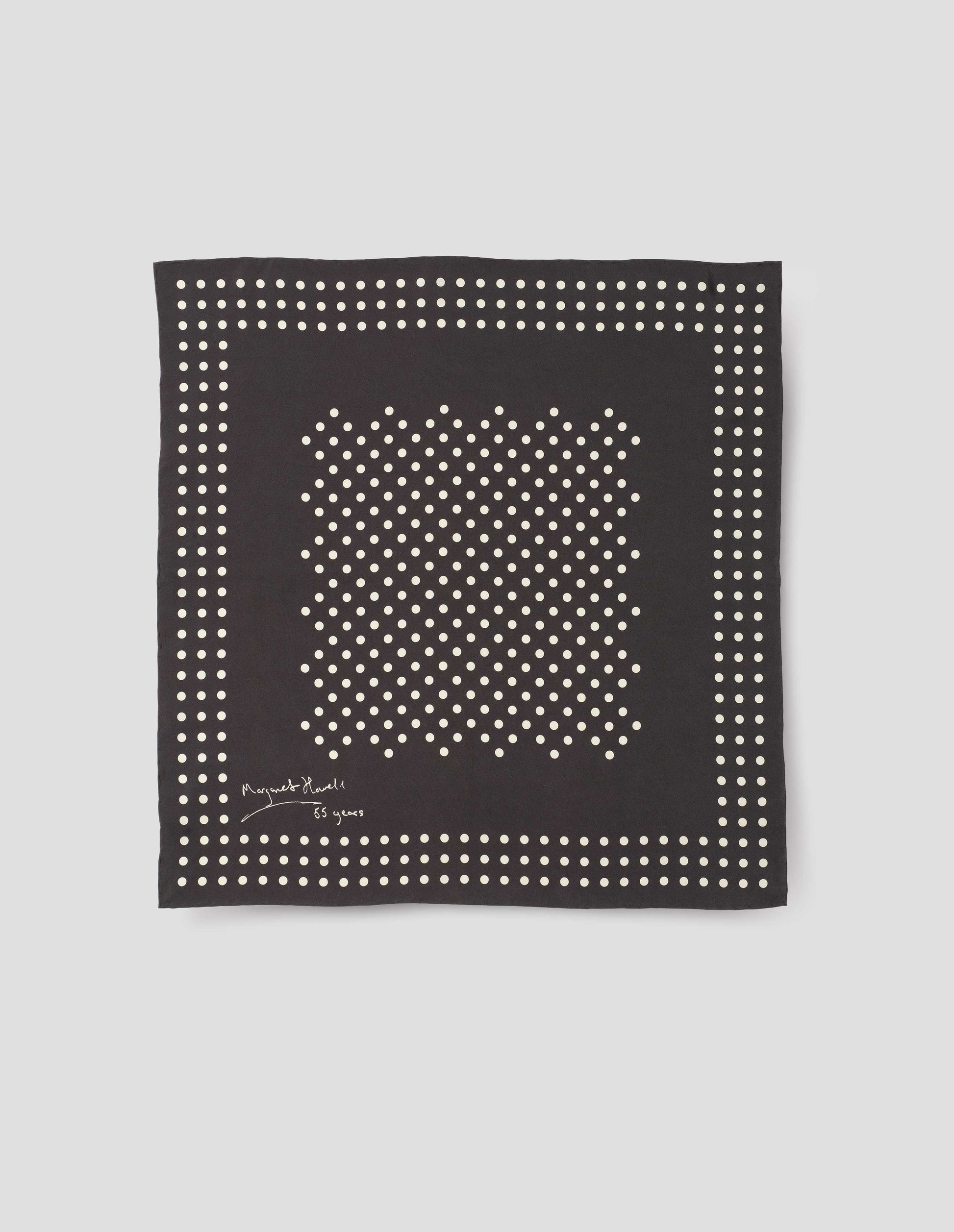 Black square silk neck scarf with white dots, hand rolled edges and Margaret Howell logo. Front flat lay view.