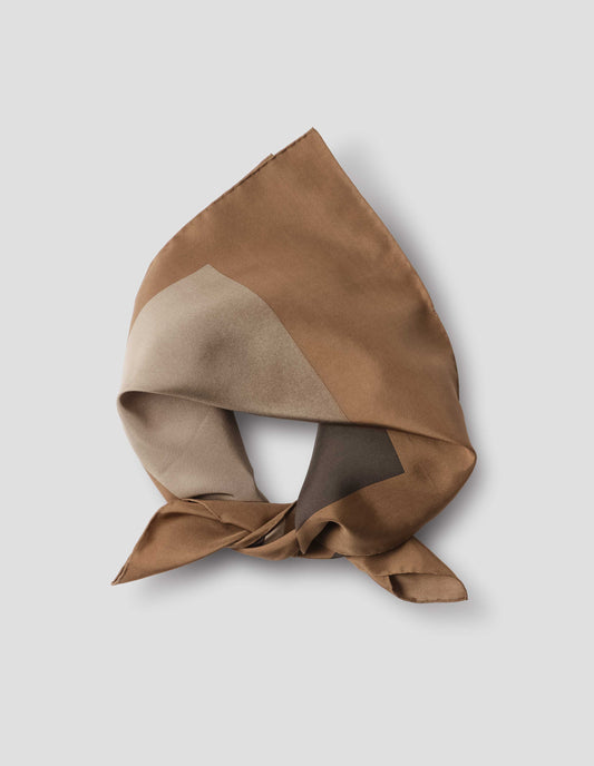 Light brown folded and tied neck scarf with contrast beige and brown collage print and hand rolled edges. Close up flat lay view.