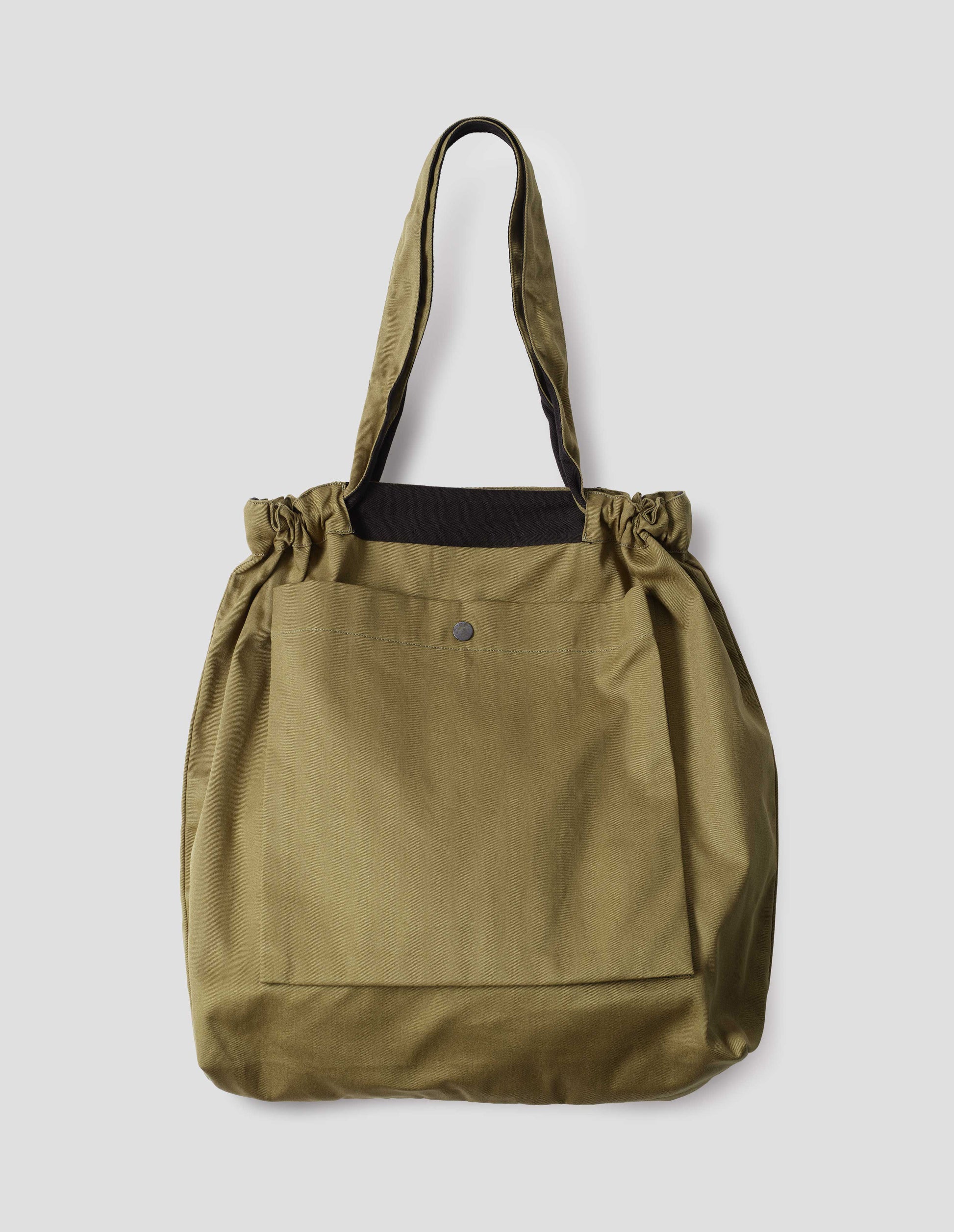 Olive green tote bag with drawcord handles, large press stud fastening bellows patch pocket and contrasting herringbone tape detailing. Front flat lay view.