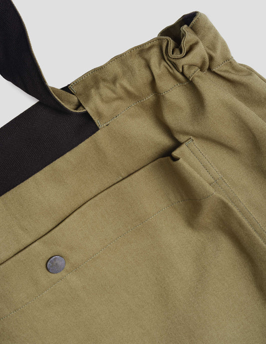 Olive green tote bag with drawcord handles, large press stud fastening bellows patch pocket and contrasting herringbone tape detailing. Fabric swatch.