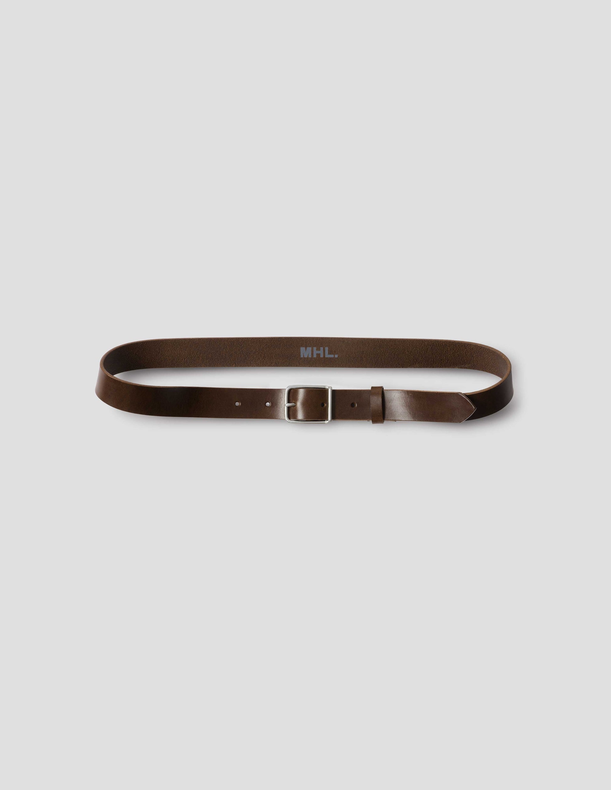 Dark brown leather belt with silver buckle, black leather strap and white MHL. logo stamped onto centre inside of belt. Front flat lay view.