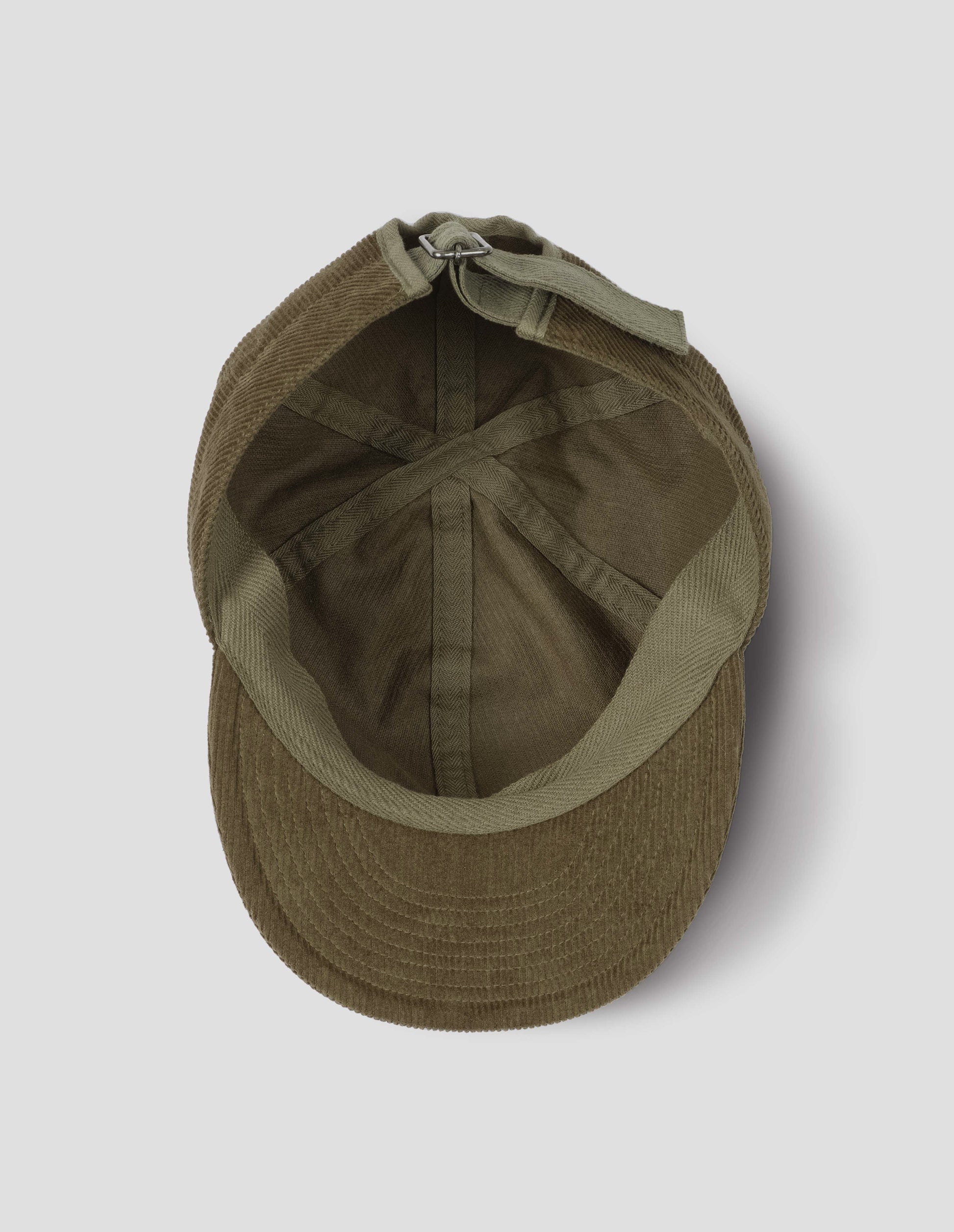 Khaki beige corduroy cap, with herringbone tape adjuster and detailing, view from above, inside flat lay.