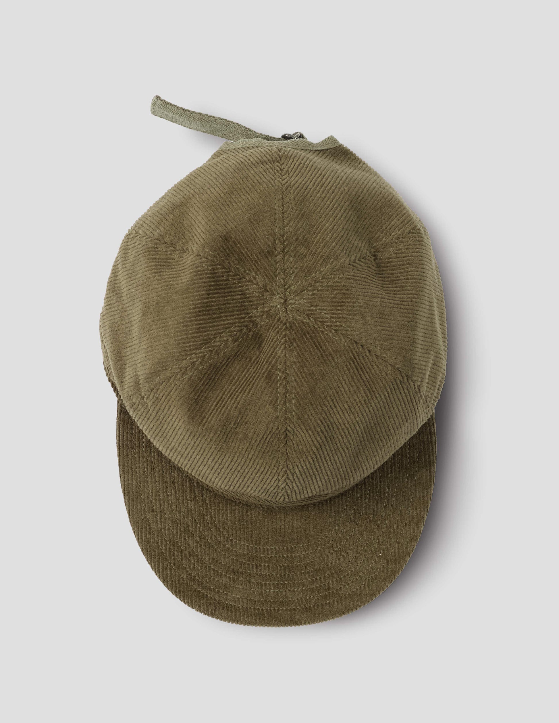Khaki beige corduroy cap, with herringbone tape adjuster, view from above flat lay.