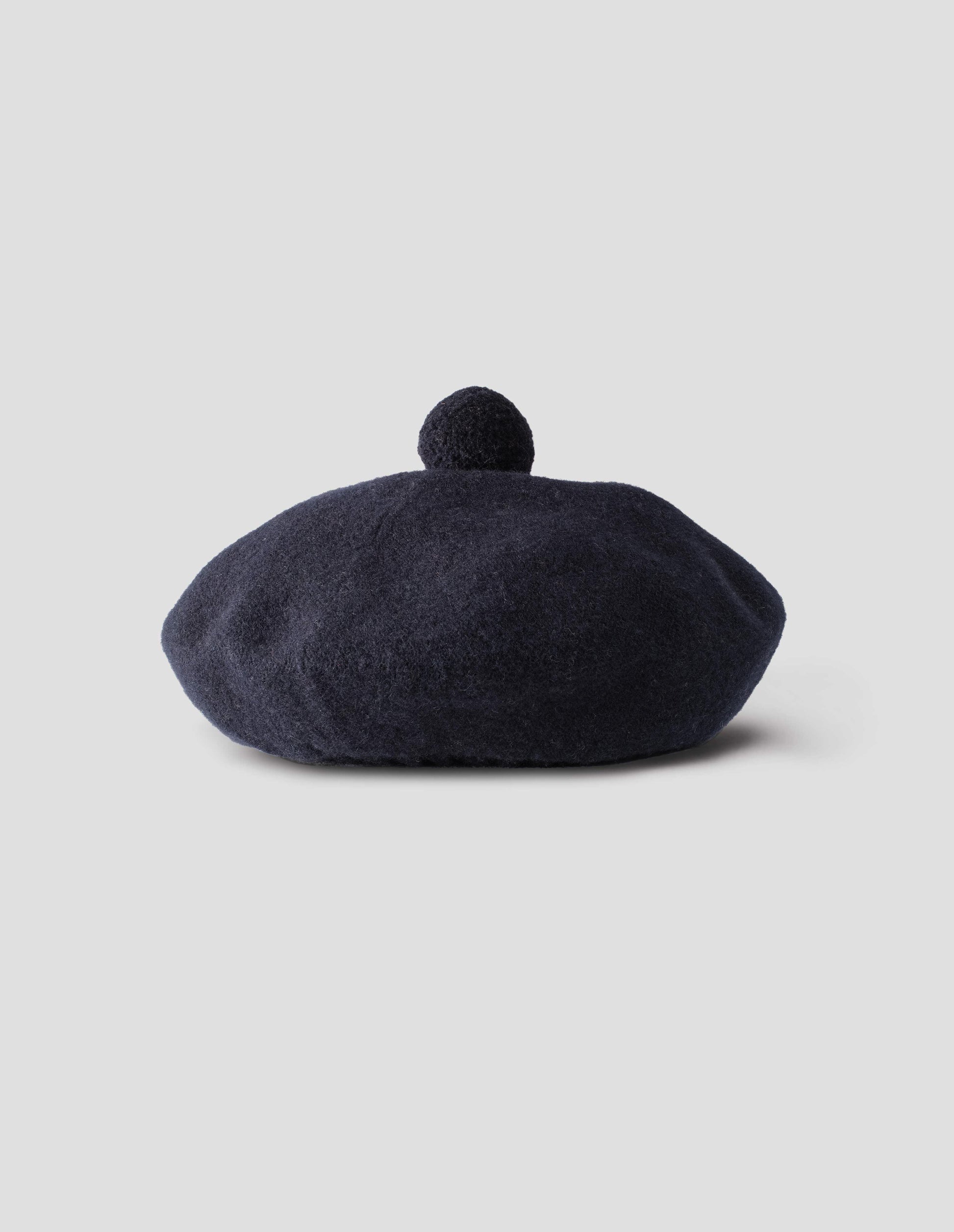 Dark navy wool tam o shanter hat with matching pom pom bobble in centre. Front flat lay view.