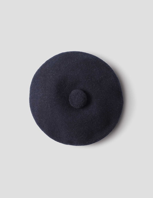 Dark navy wool tam o shanter hat with matching pom pom bobble in centre. View from above flat lay view.