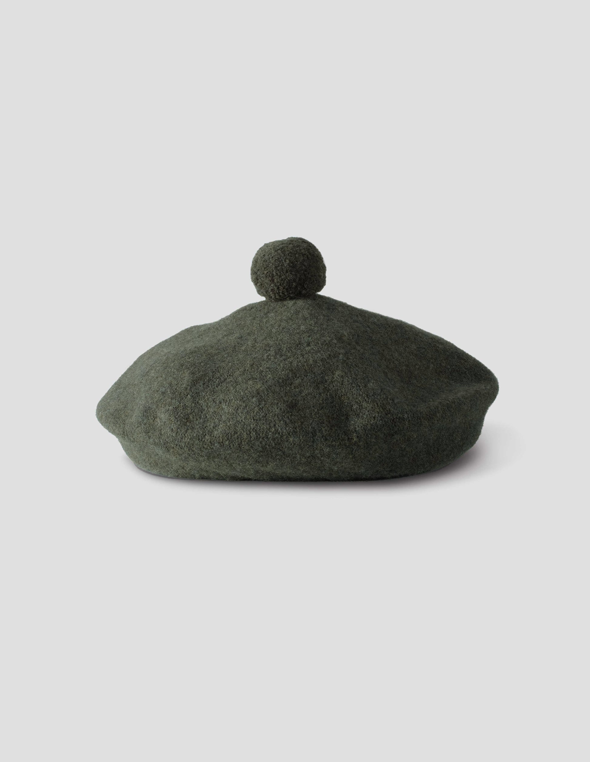 Green wool tam o shanter hat with matching pom pom bobble in centre. Front flat lay view.