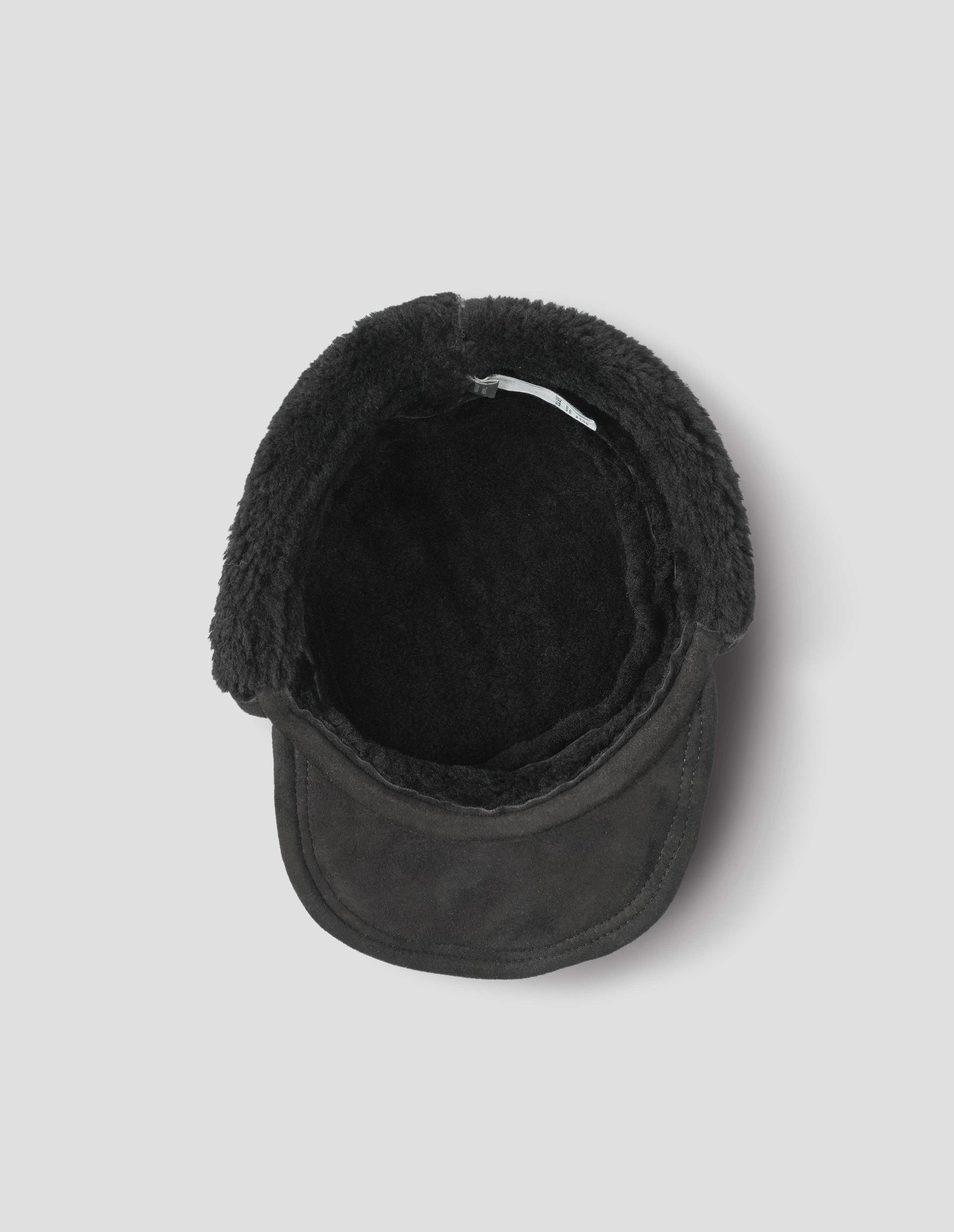 Black curly merino shearling press stud cap with peak. Inside flat lay view.