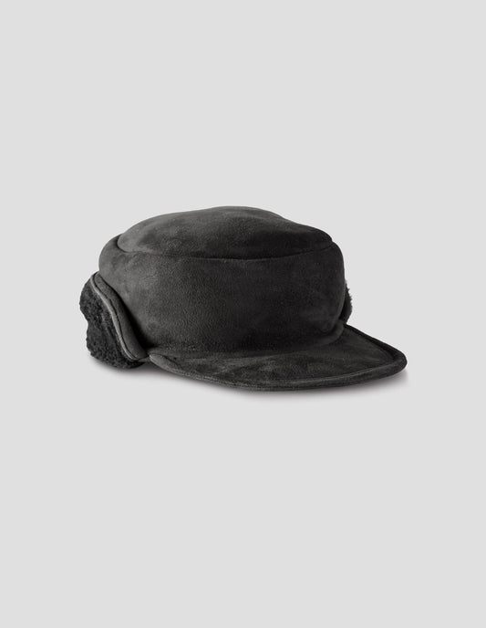 Black shearling press stud cap with peak and black curly merino sheepskin ear flaps. Front flat lay view.