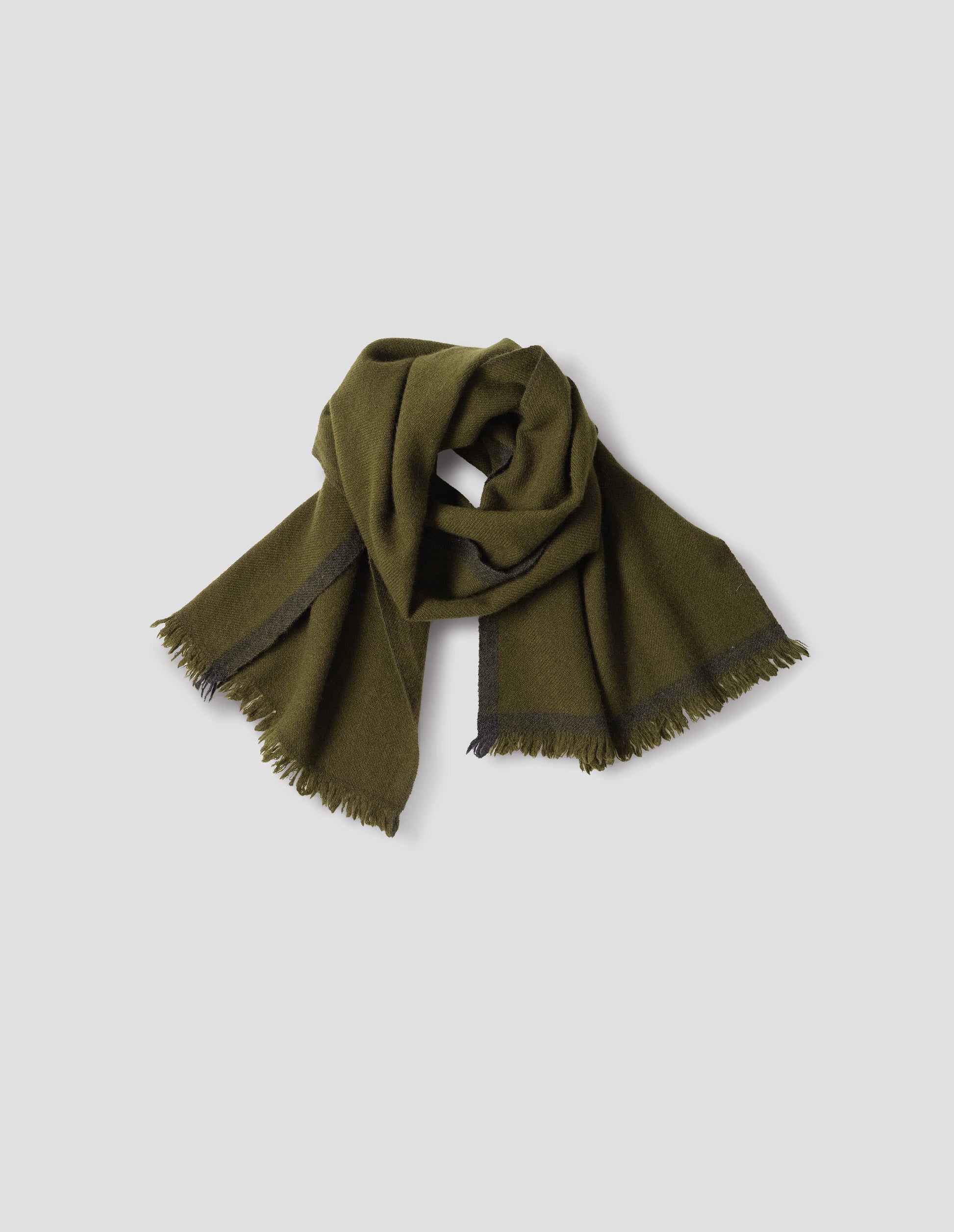 Green knitted scarf with fringe and dark green contrast edge. Front flat lay view.