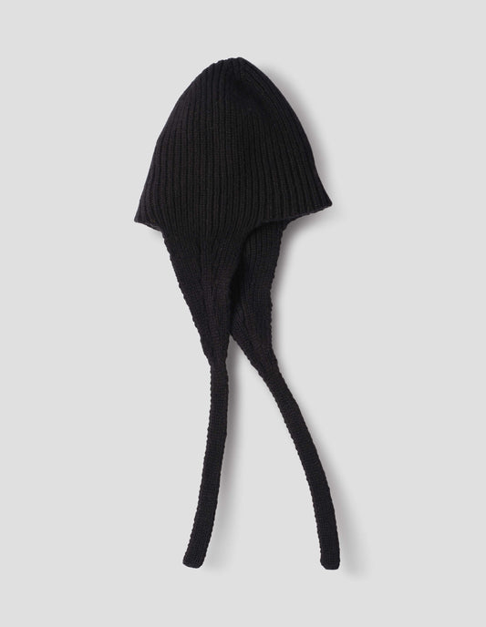 Black soft spun merino knitted ribbed hat with ear flaps and tie detail. Side flat lay view.
