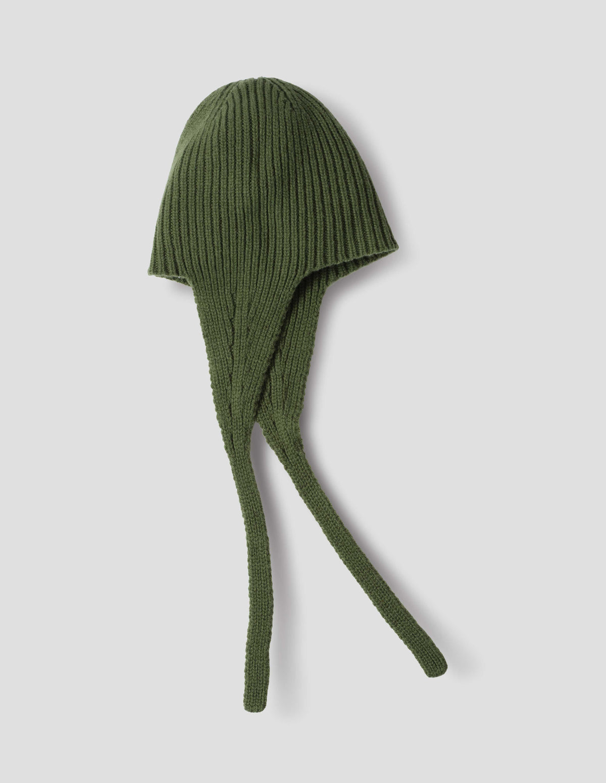 Green soft spun merino knitted ribbed hat with ear flaps and tie detail. Side flat lay view.