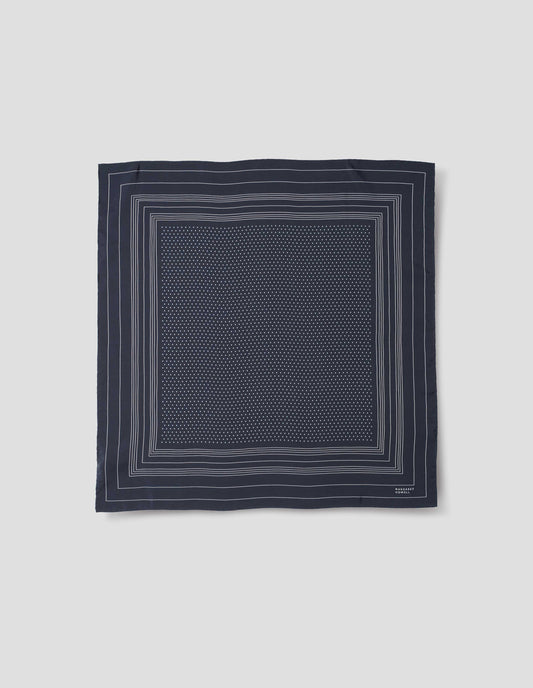 Dark blue square silk neck scarf with white border stripes with white dots inside hand rolled edges and white Margaret Howell logo in right corner. Front flat lay view.