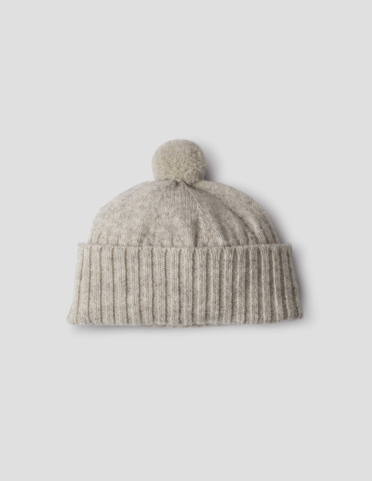 Beige knitted Shetland wool bobble hat with rib turned up cuff, front flat lay view.