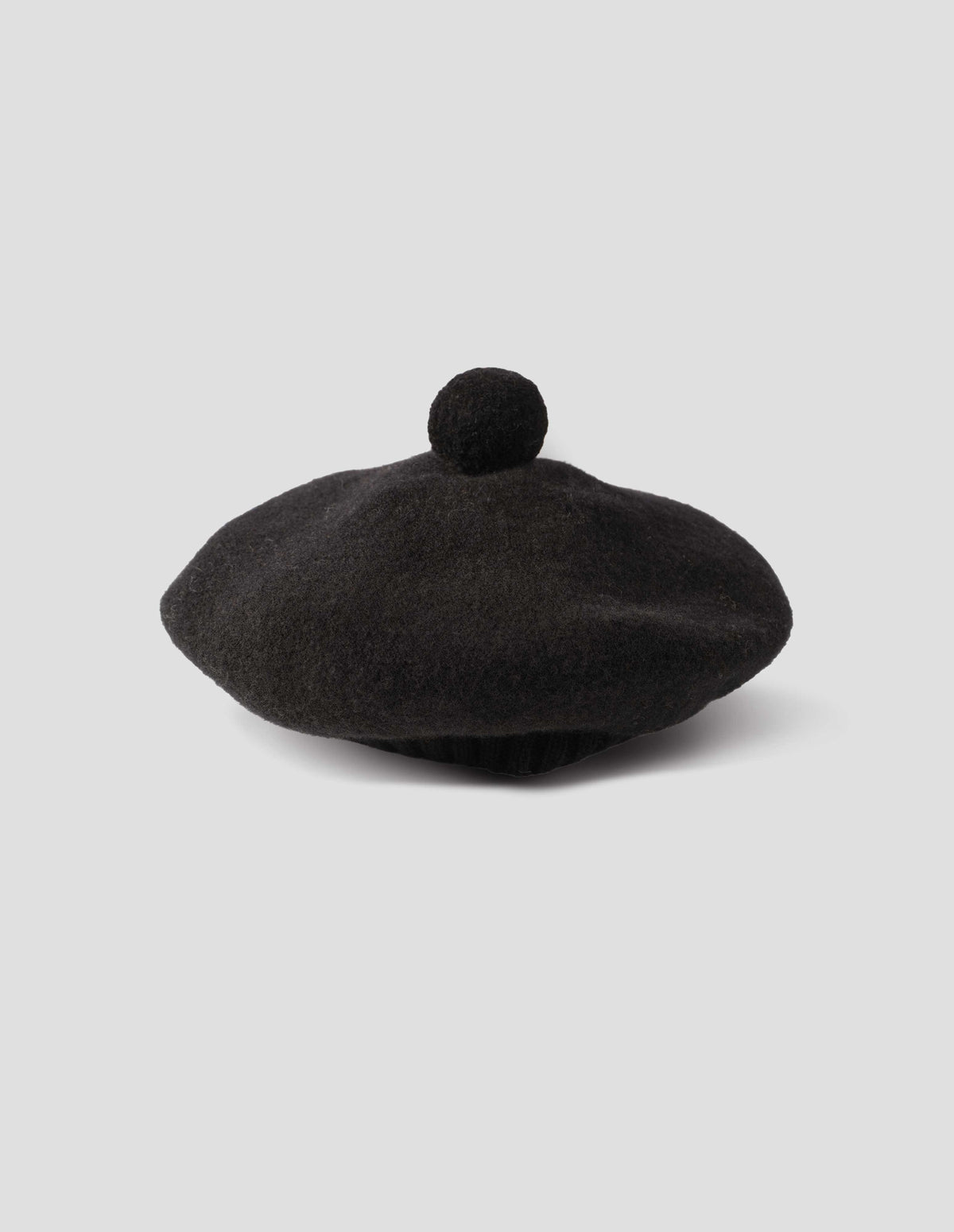 Black wool tam o shanter hat with matching pom pom in centre, side view.