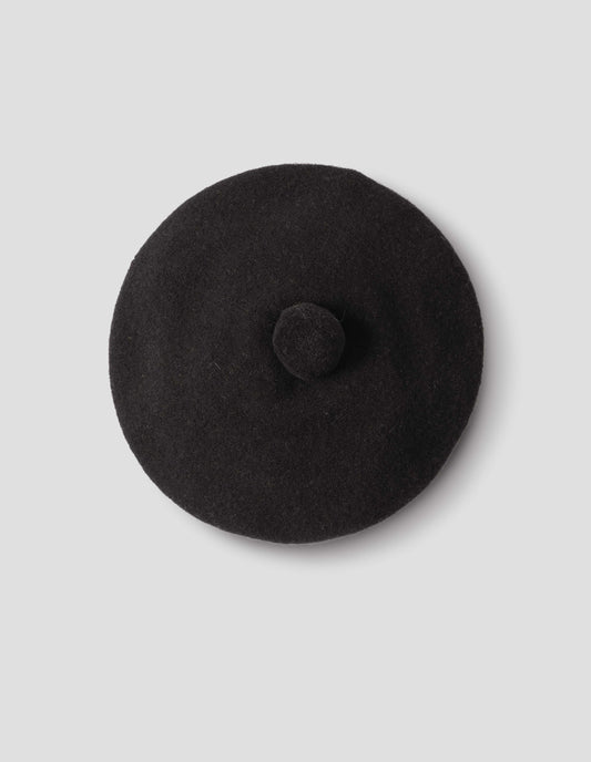 Black wool tam o shanter hat with matching pom pom in centre, from above flat lay view.
