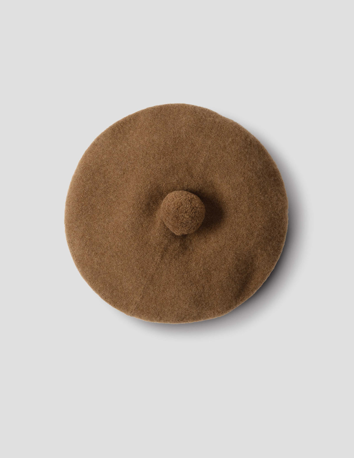 Brown wool tam o shanter hat with matching pom pom in centre, from above flat lay view.