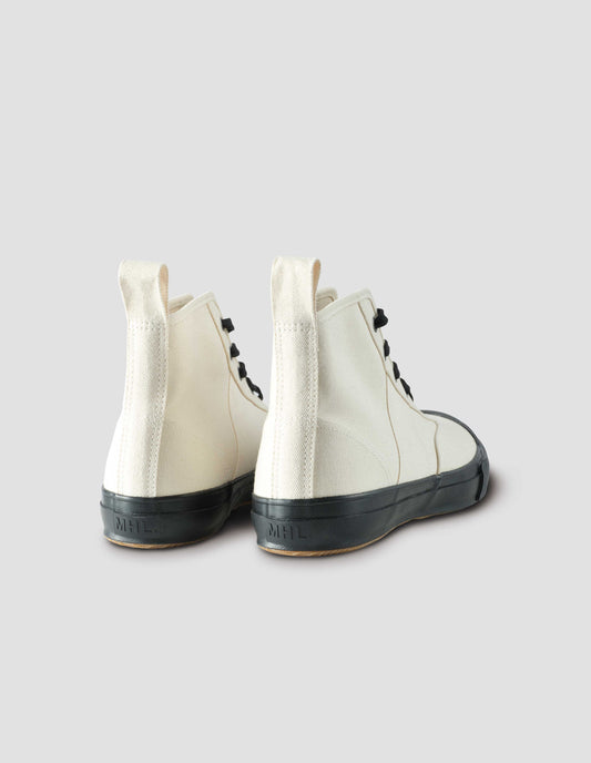 Off white high top canvas trainers with metal eyelets, contrasting black laces, canvas heel loop and contrasting black rubber sole. Back view flat lay.