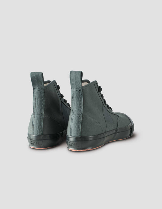 Greenish grey high top canvas trainers with metal eyelets, contrasting black laces, canvas heel loop and contrasting black rubber sole. Back view flat lay.