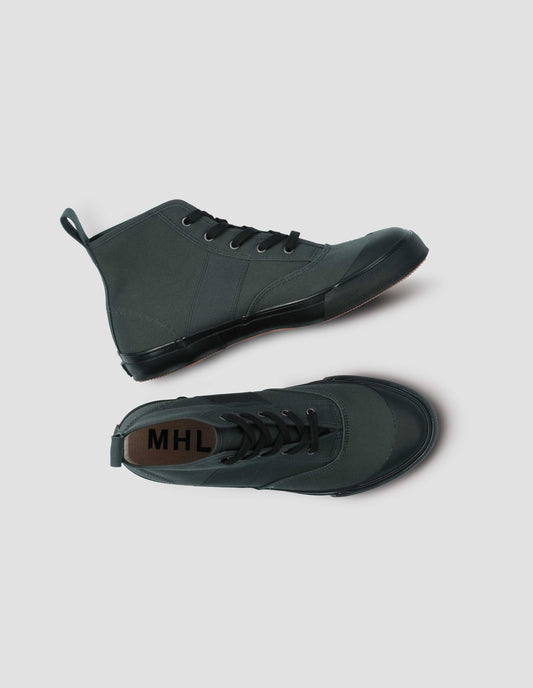 Greenish grey high top canvas trainers with metal eyelets, contrasting black laces, canvas heel loop and contrasting black rubber sole. View from above flat lay.