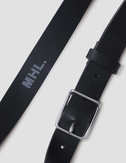 Black leather belt with silver buckle, black leather strap and white MHL. logo stamped onto centre inside of belt. Close up detail flat lay view.
