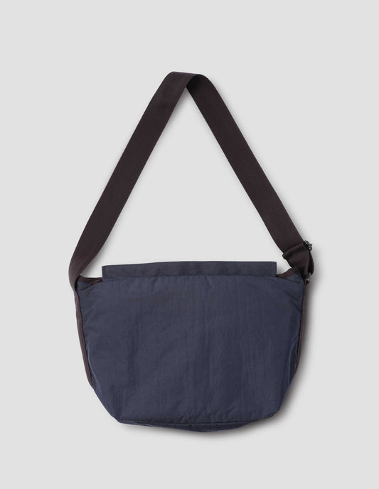 Navy blue bag with contrast black herringbone tape shoulder strap and Velcro closure. Back flat lay view. 