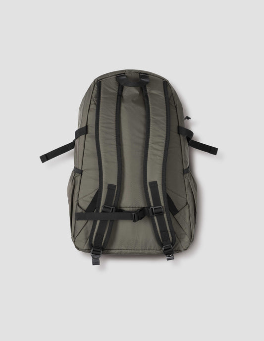Khaki green nylon ripstop backpack with side pockets, contrasting black carry handle and contrasting black chest belt. Back flat lay view.
