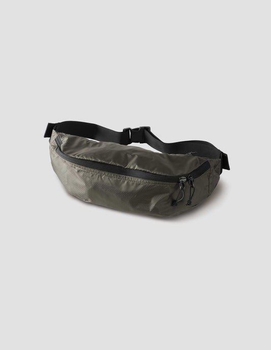 Khaki green nylon ripstop waist pouch with contrasting black adjustable strap and contrast black zip closure. Side flat lay view.