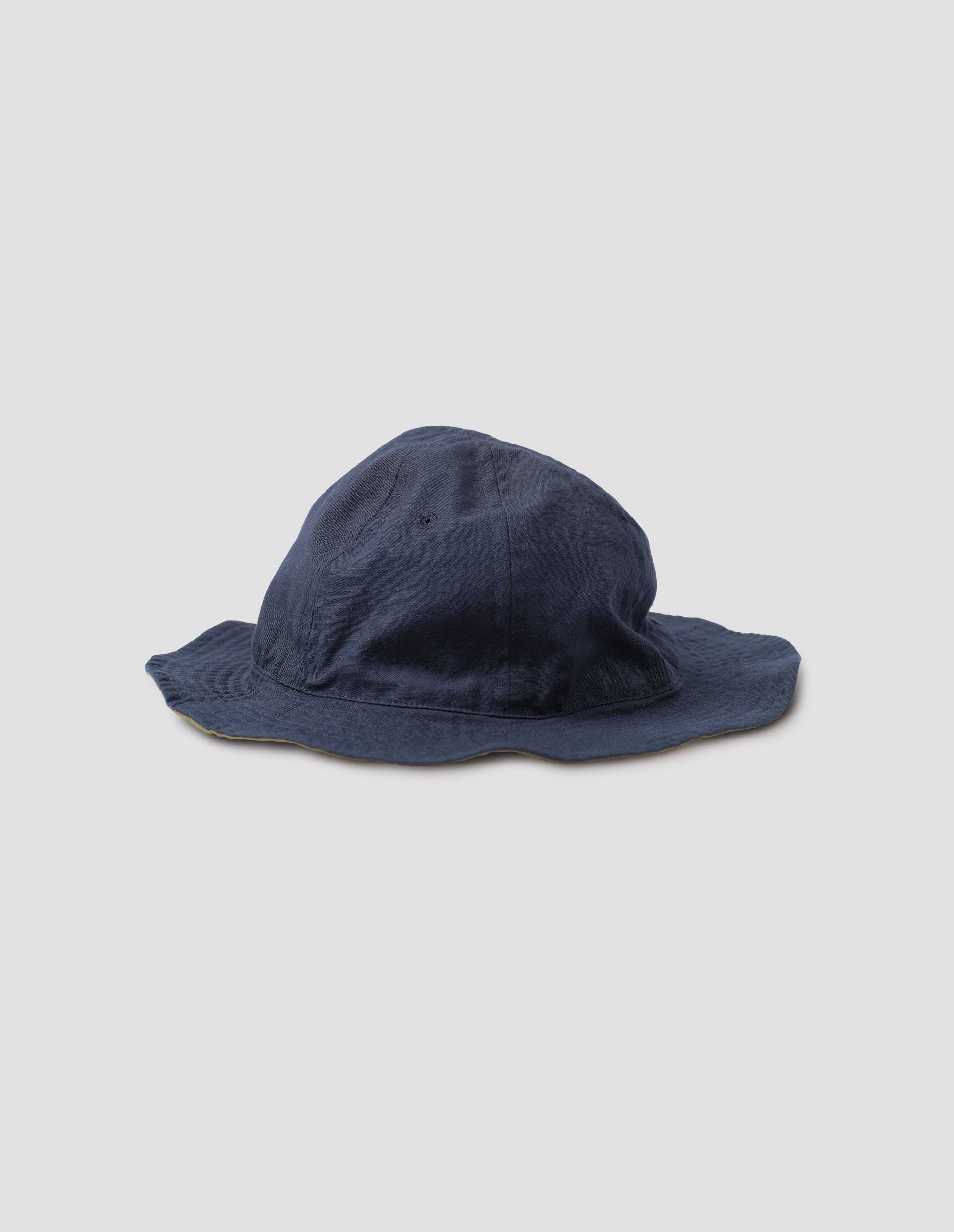 Dark blue cotton hat showcasing the flexible reversible design. Side view.