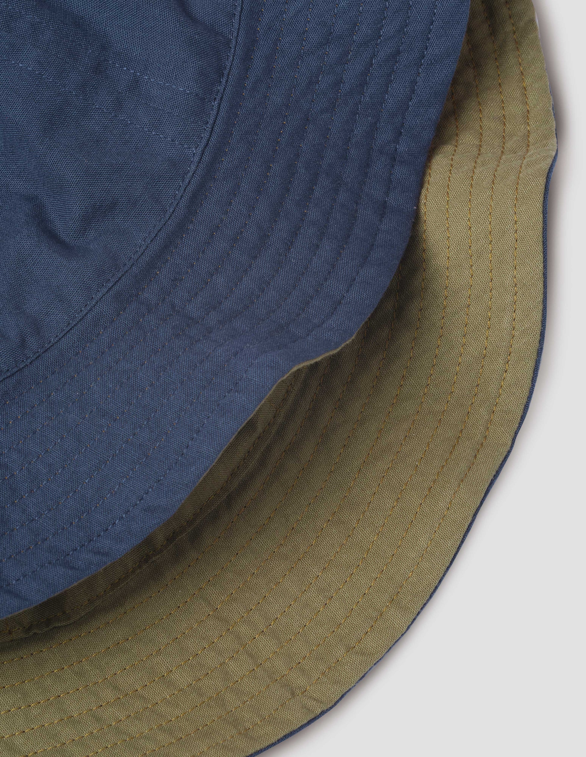 Detail of both sides of the hat showing the dark blue and olive green brims with stitching. Close up view.