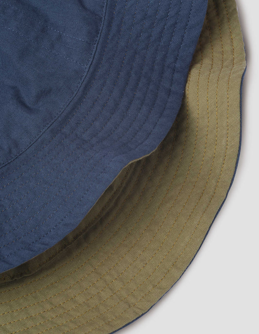 Detail of both sides of the hat showing the dark blue and olive green brims with stitching. Close up view.