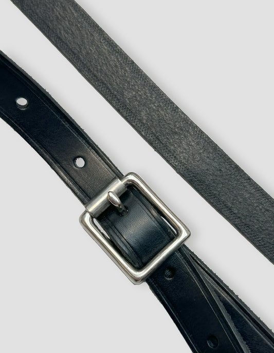 Detail of the one pin roller buckle showcasing the top and flesh sides of the leather with punched holes. Close up view.