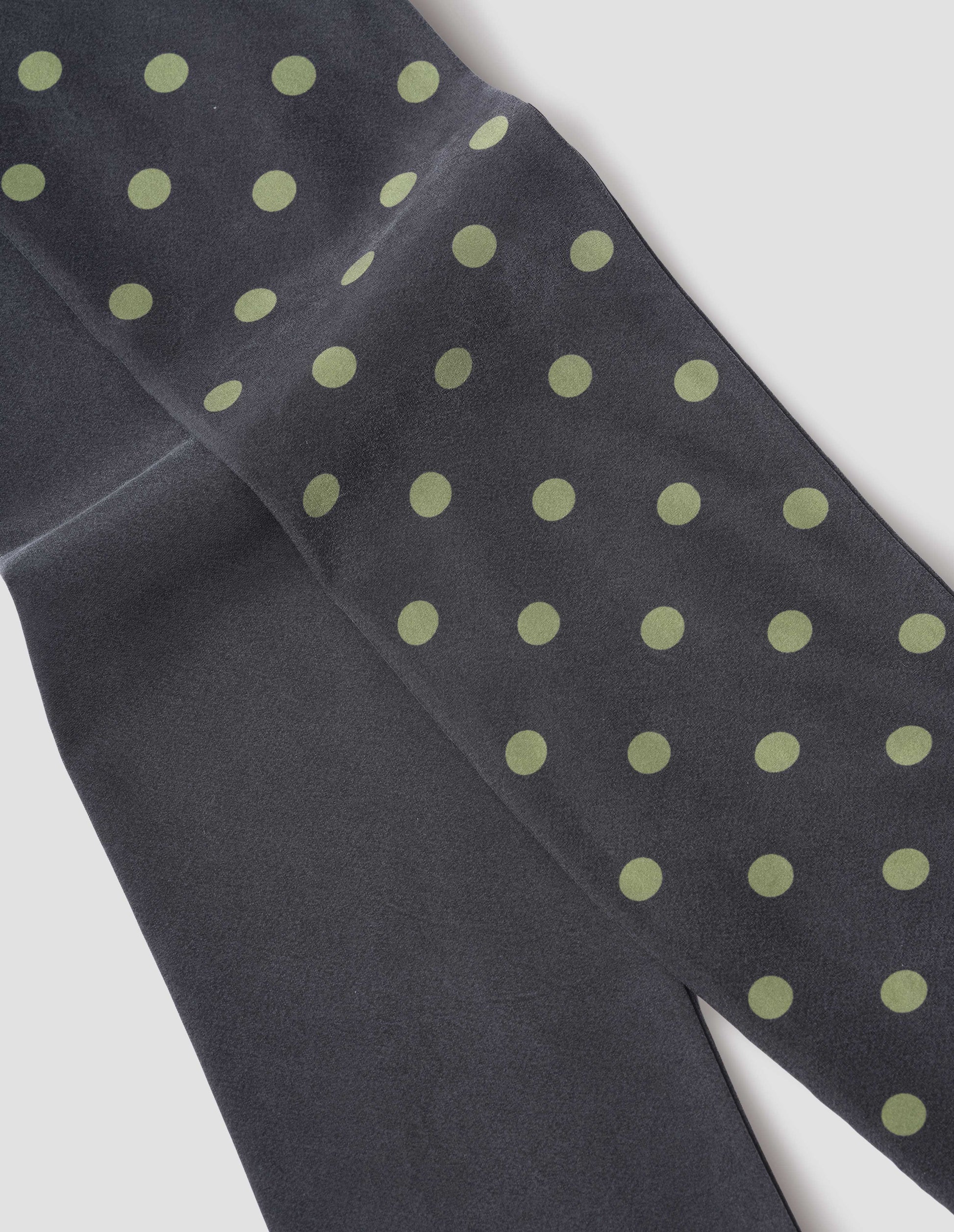 Black silk scarf with light green spots on one side, fabric swatch.