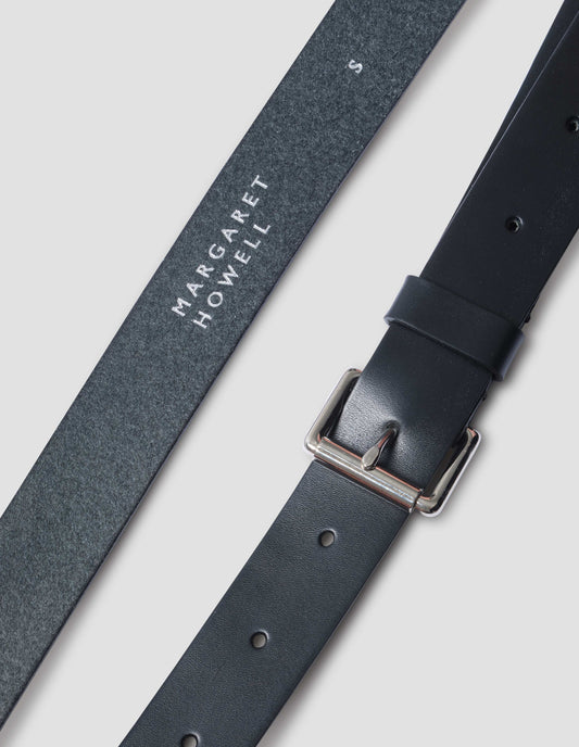 Black leather belt with silver buckle and black leather strap. Close up detail shot.