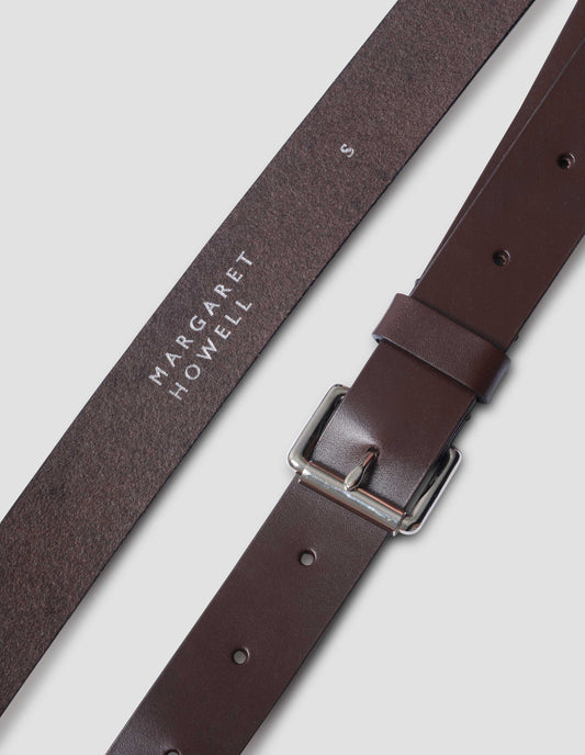 Dark brown leather belt with silver buckle and dark brown leather strap. Close up detail shot.