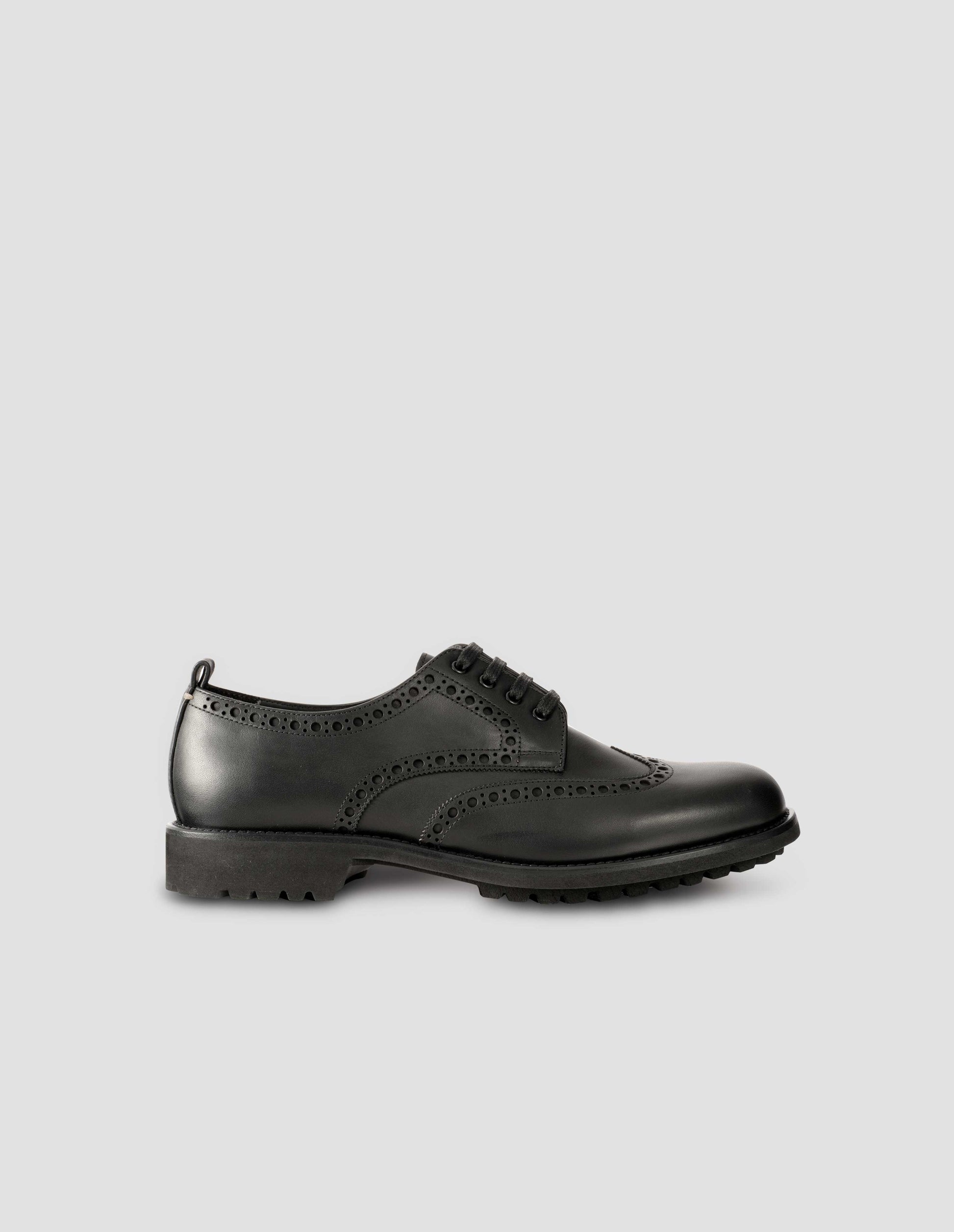 Single matt black leather brogue with black laces and lightweight rubber commando sole. Side view flat lay.