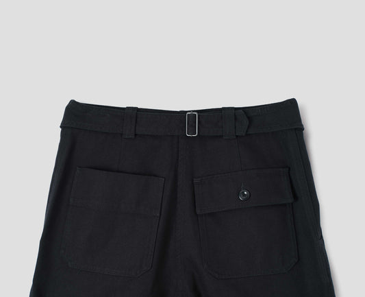 Black cotton wool trousers with self waistband with cinch back and belt loops, button through flap patch and patch back pockets. Back flat lay view.