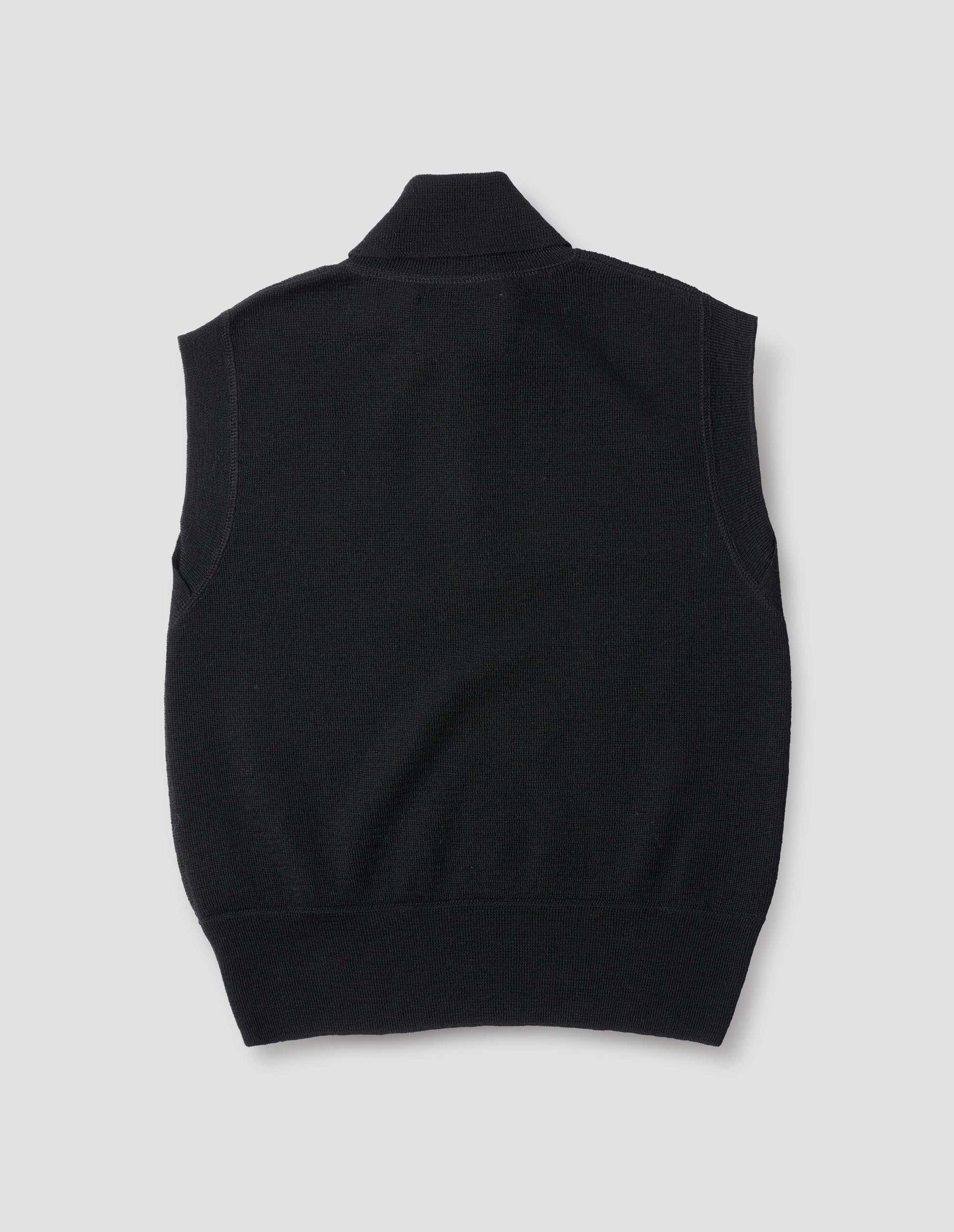 Black wool slipover, with half zip mock turtleneck and flatlock stitch detailing on seams. Back flat lay view.