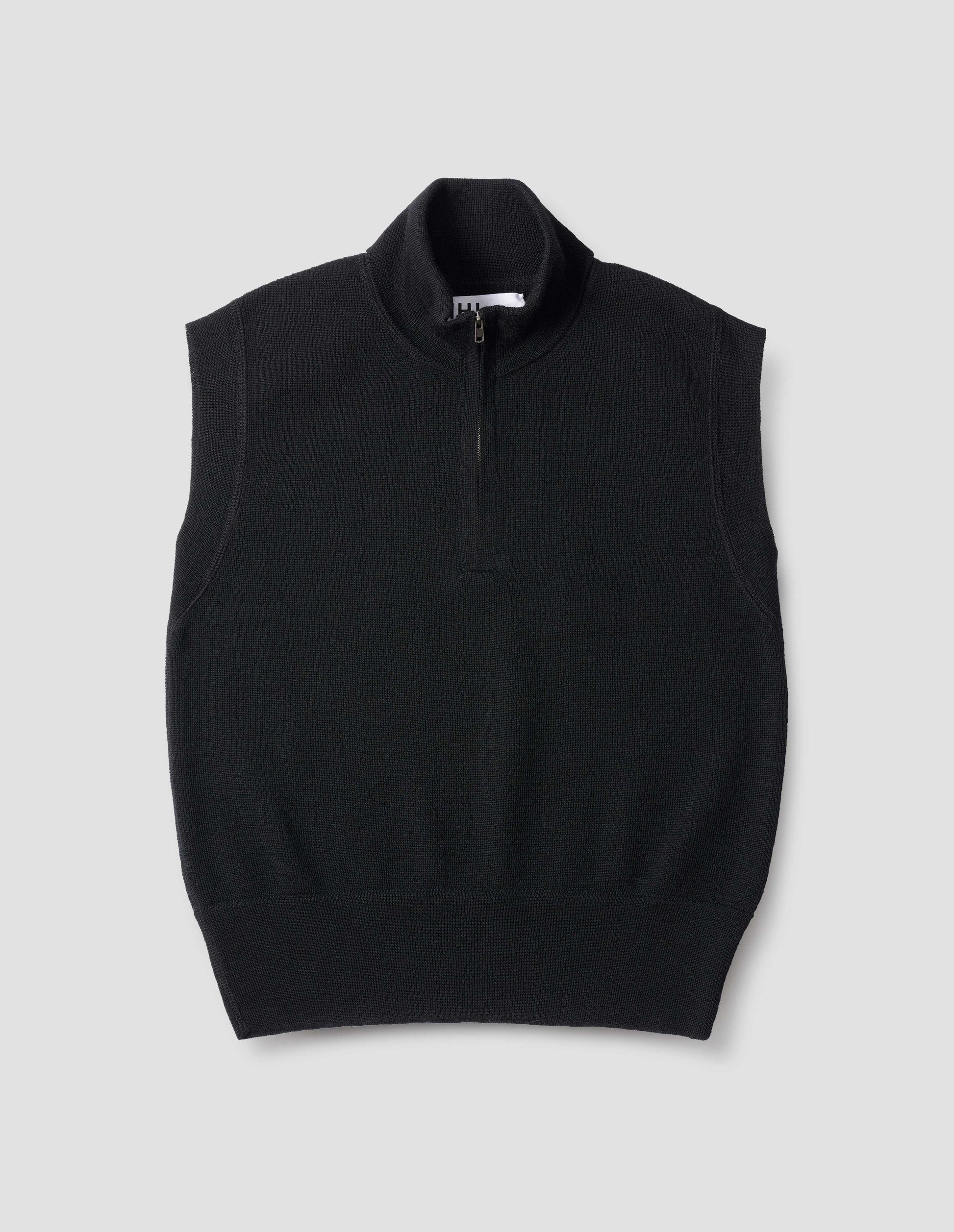 Black wool slipover, with half zip mock turtleneck and flatlock stitch detailing on seams. Front flat lay view.