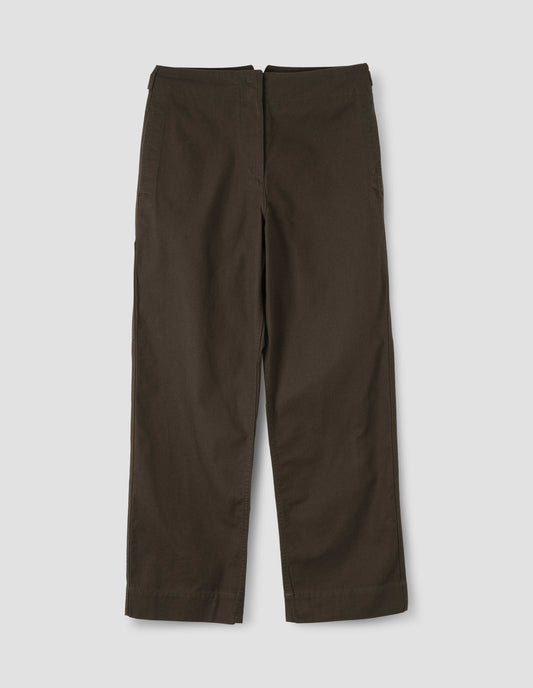Dark brown cotton trousers with zip fly with button through fastening, stitch through waistband, and concealed side pockets. Front flat lay view.
