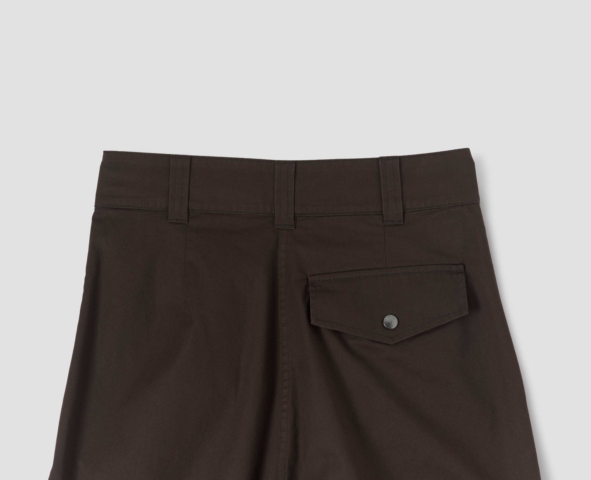 Dark brown pleated trousers with popper fastening back flap pocket and belt loops. Back flat lay view.